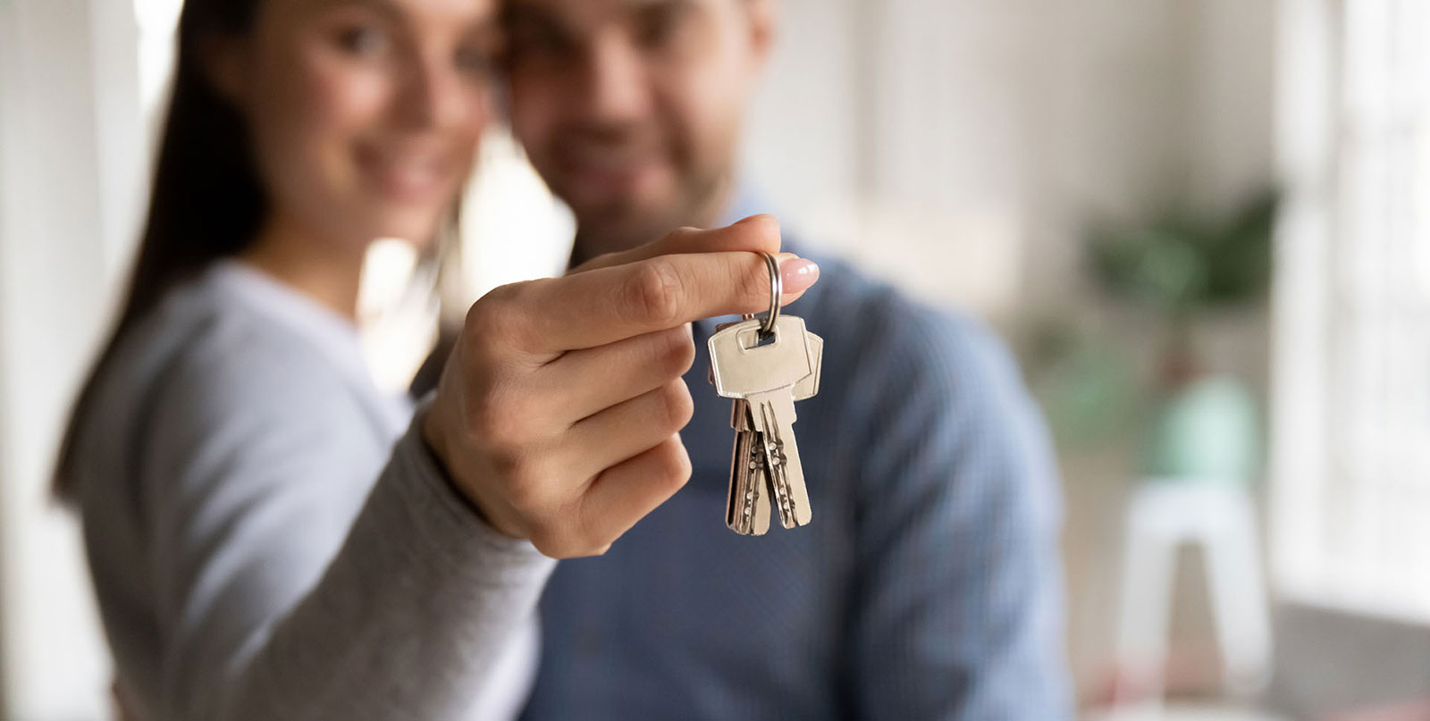 a happy couple in the background holding a key